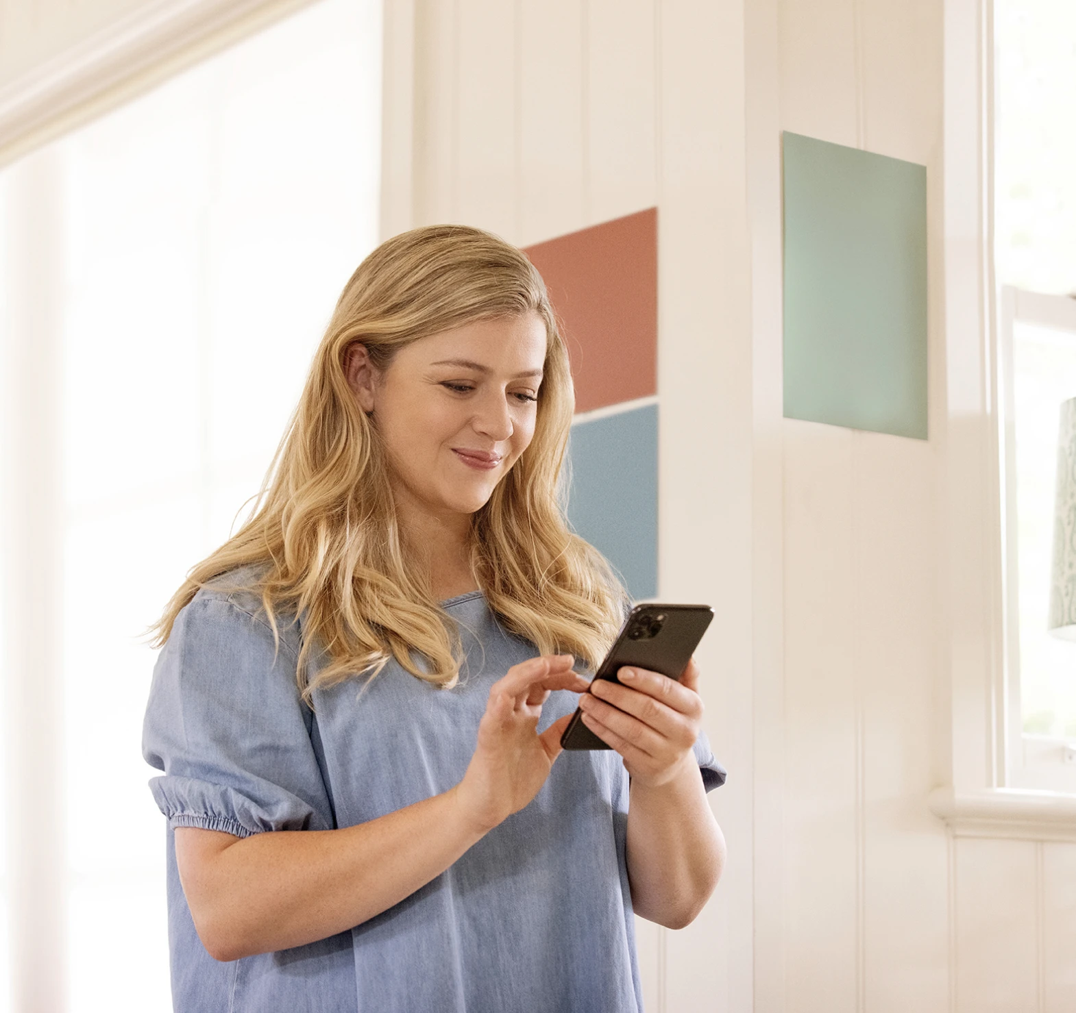 Woman on the phone to Dulux customer service with sample stickers in the background on the wall