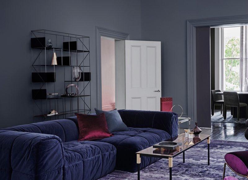 A navy couch set in front of a dark grey backdrop