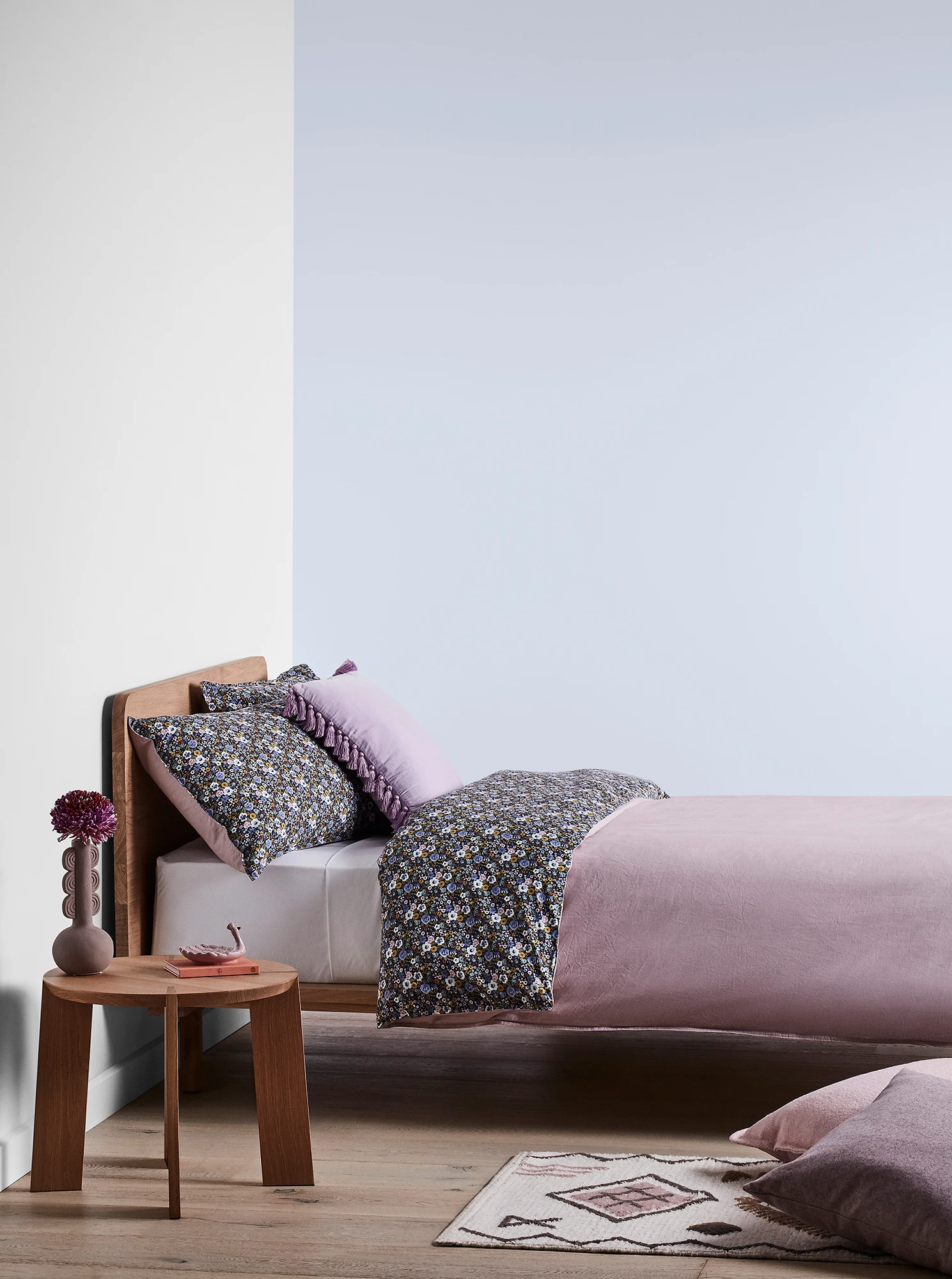 Purple-blue bedroom with timber bed and side table and purple linens.