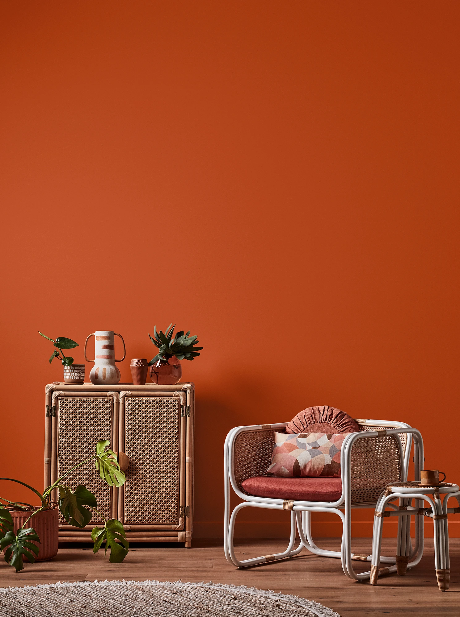 Orange living room with natural rattan cabinet and white rattan table and chair with pink cushions