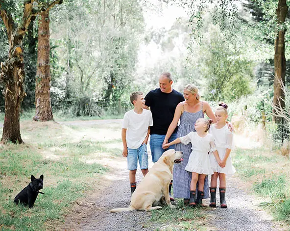 Family stand on forest walkway with golden retriever dog