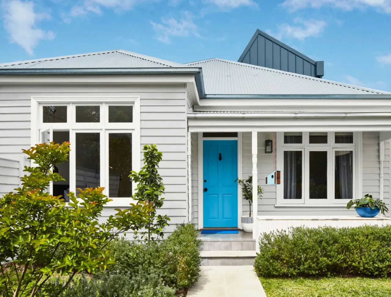 Neutrally painted exterior of home with picket fence in front and peach coloured front door.