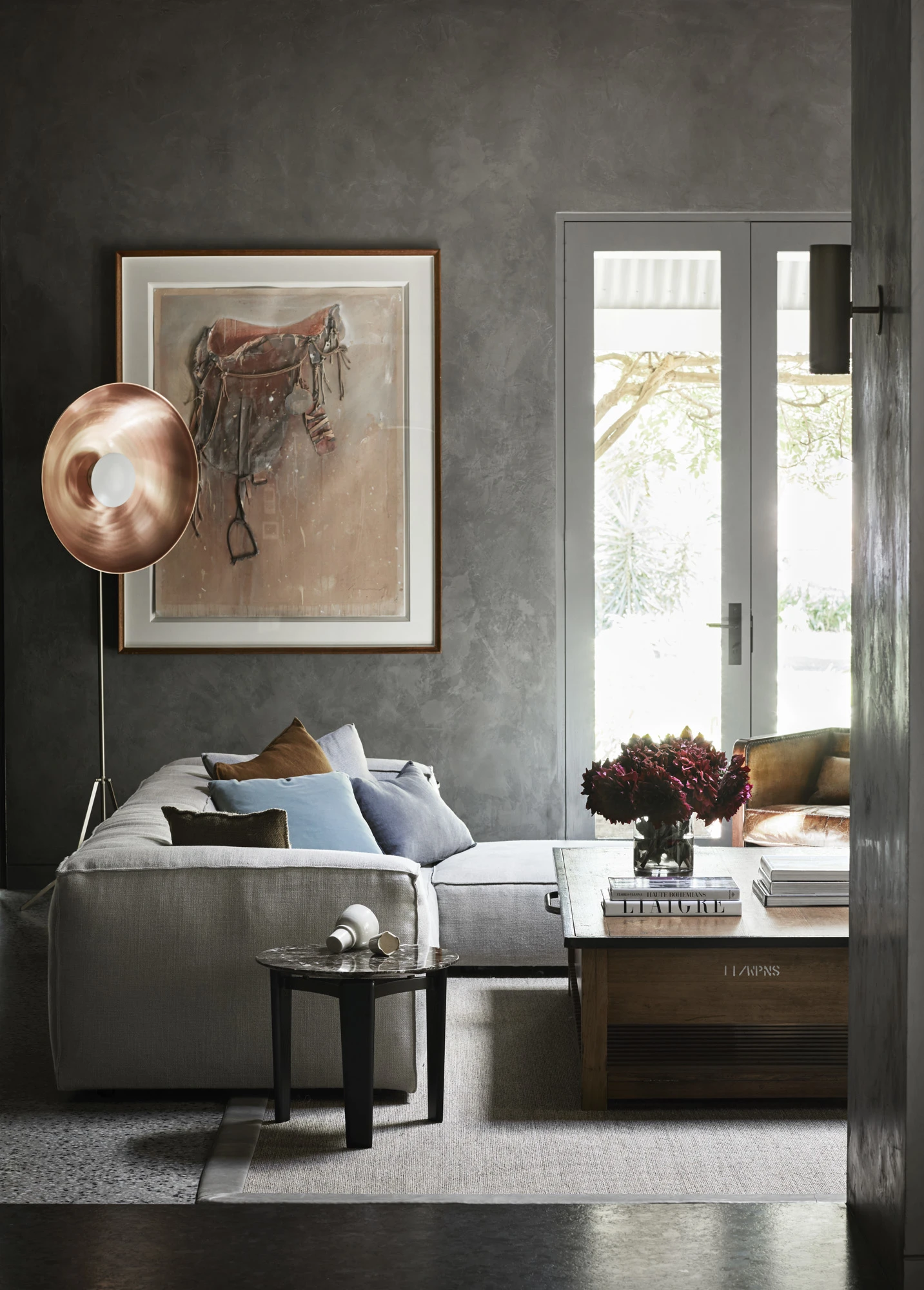 Grey living room with grey couch, copper lamp, artwork and white french doors.