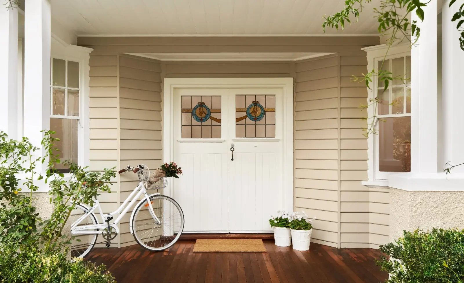 White door against weatherboard style home with bike leaning against wall. 