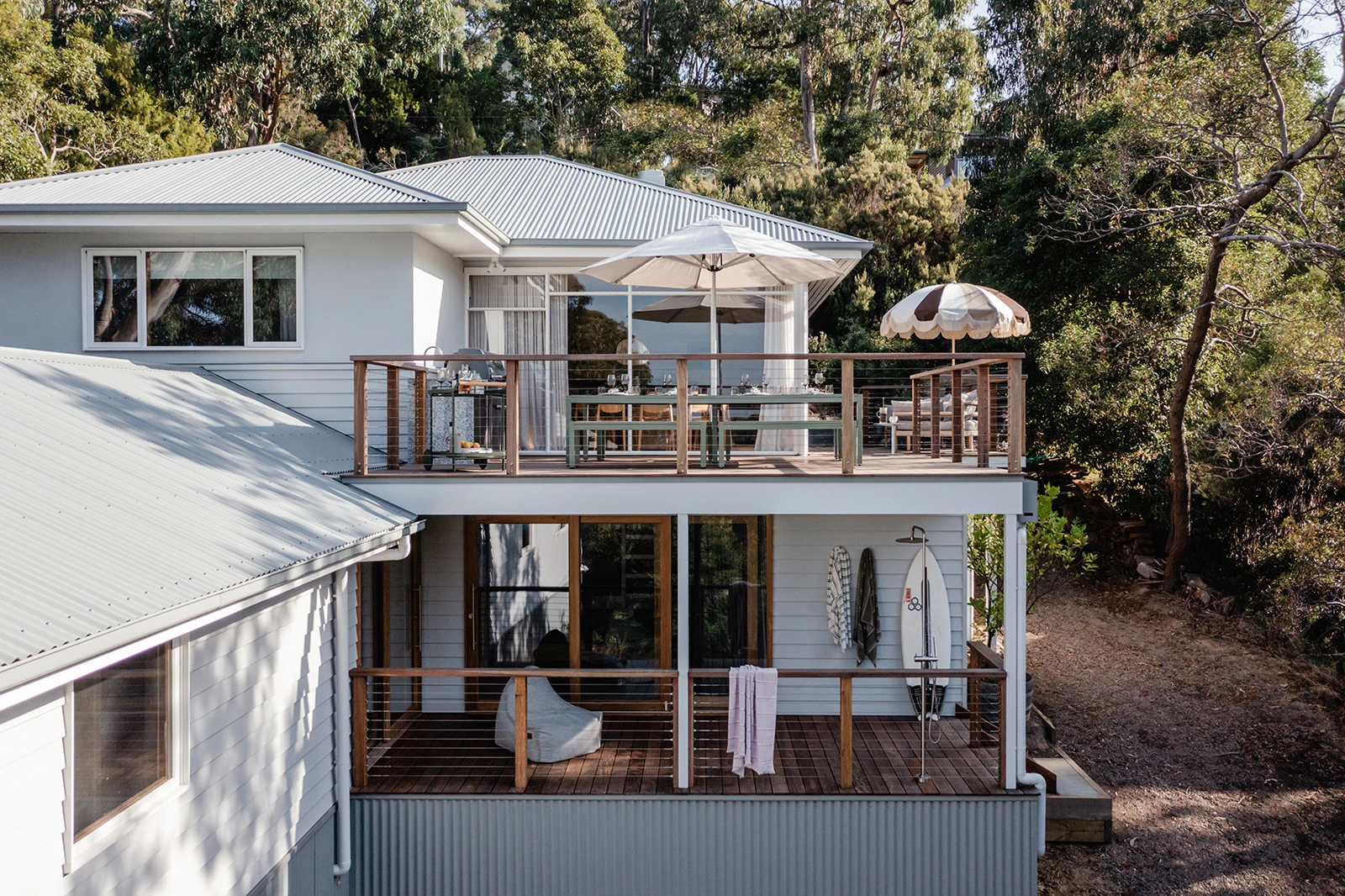 Image of double storey beach house with sun umbrella on deck