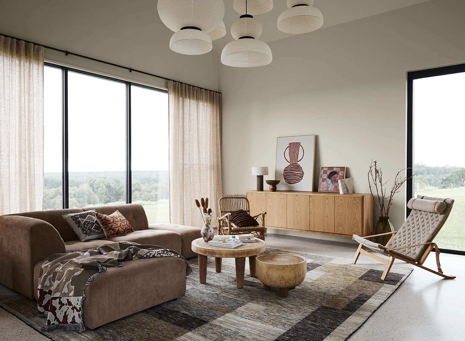 Neutral living room with brown corner couch and large windows letting in plenty of light