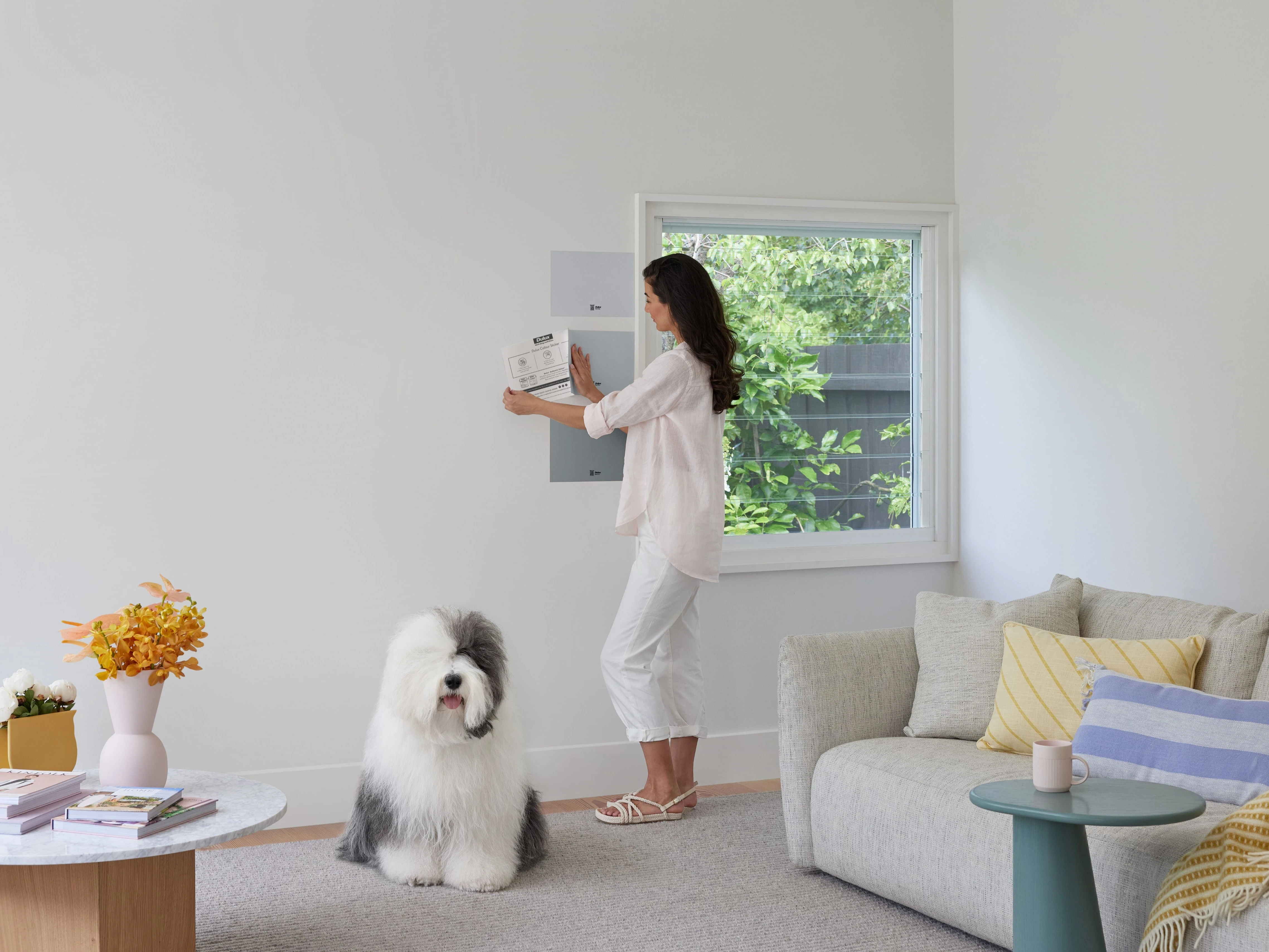 Woman using Dulux non-marking colour sample stickers on white wall