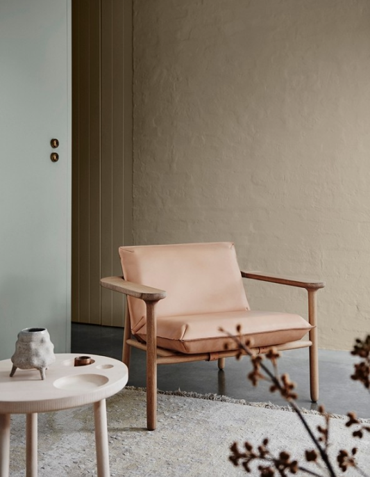 A neutral coloured arm chair with timber legs in a Japandi living room
