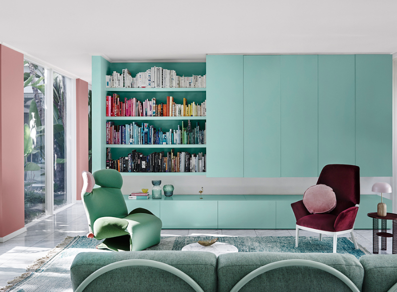 Ceiling and trim in Dulux Vivid White, cabinetry in Dulux Solution, in-built bookshelf with four shelves and multicoloured books, green armchair, maroon velvet armchair, green couch, tiled floor