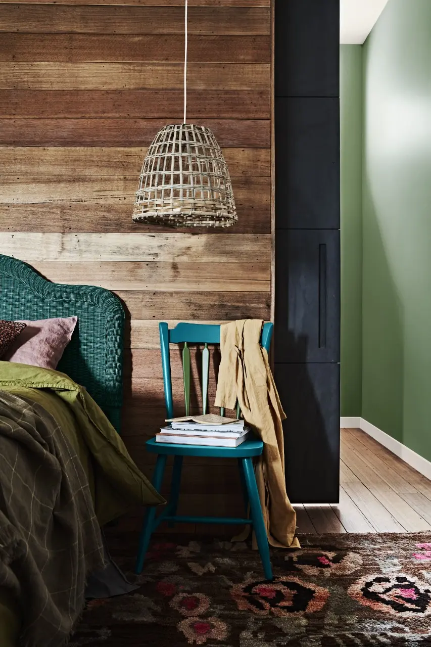 Bedroom with wooden feature wall, green wooden kitchen chair and green wall
