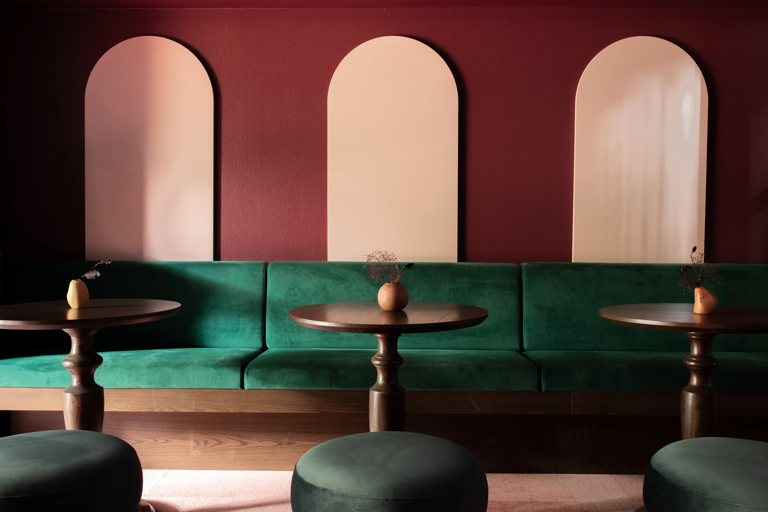 Green velvet bench seat, round tables, maroon and pink wall