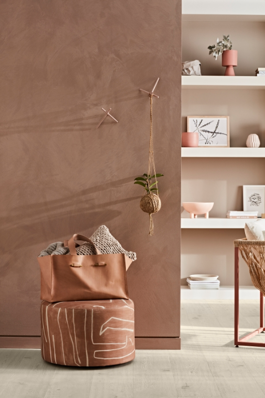 Living area in neutrals and browns with built-in bookshelf, brown ottoman and leather tote.