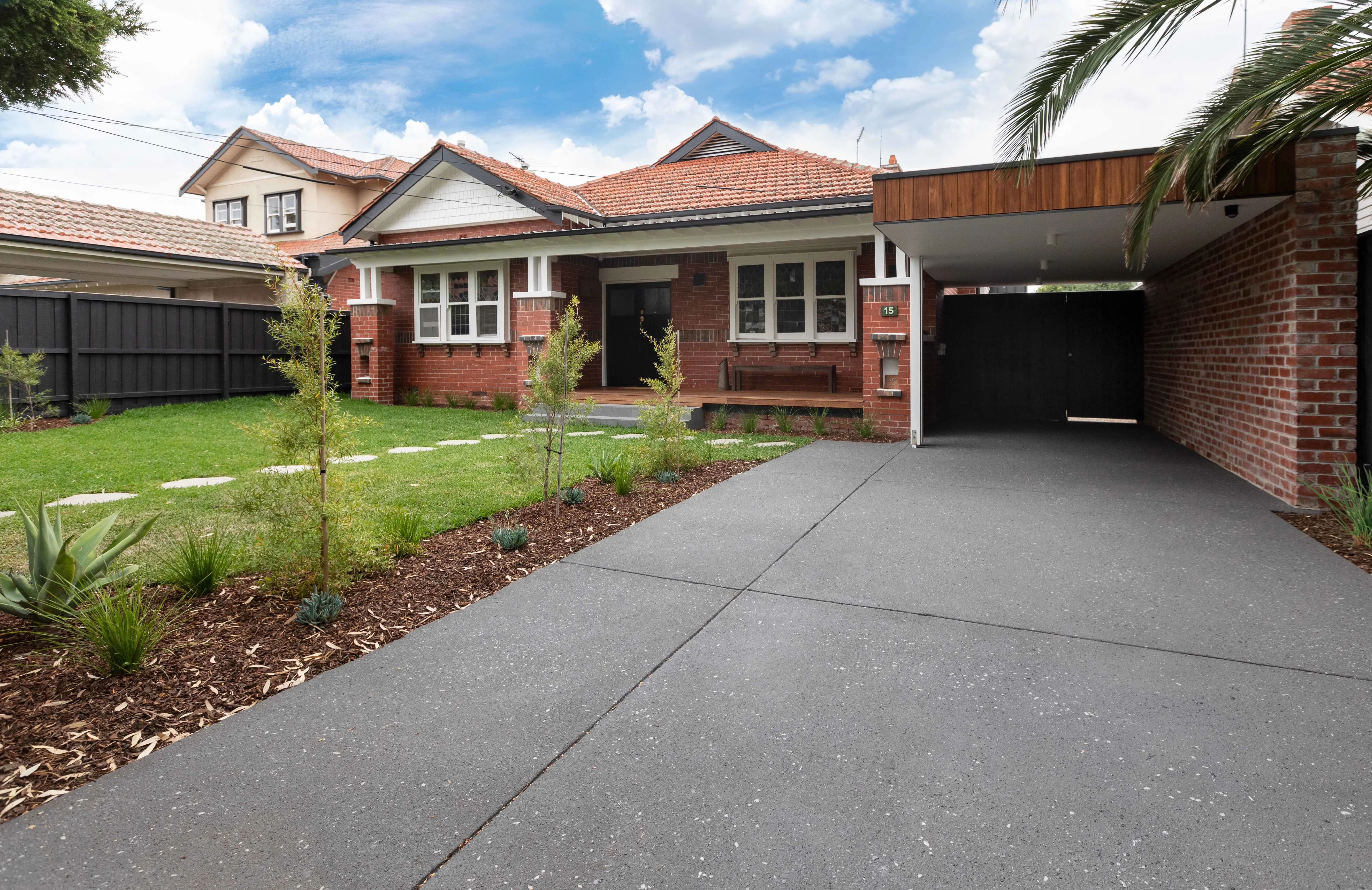 Red brick house with black and silver-flecked driveway.