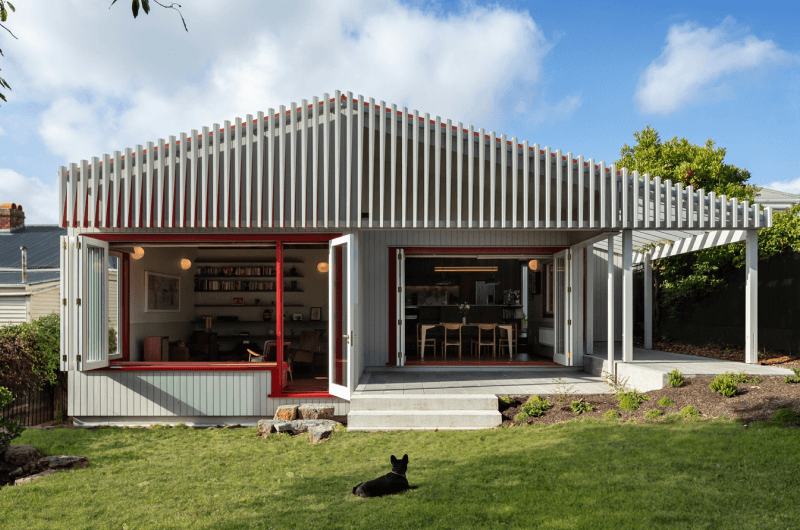 Grey single storey house with red trim. Bi-fold windows and doors.