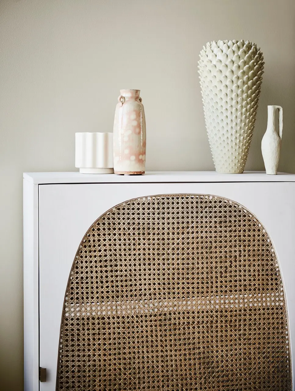 White cabinet with rattan insert in living area.