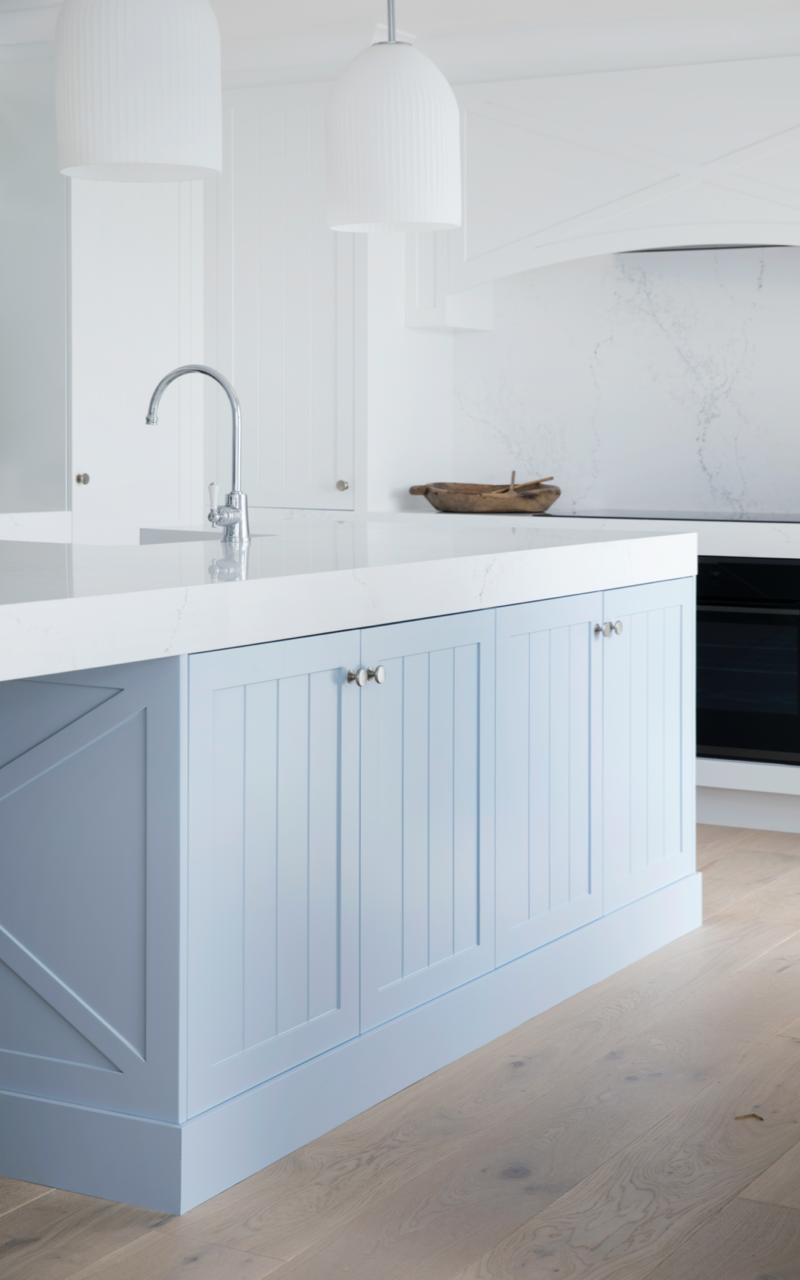 Soft blue Hamptons style kitchen island cabinetry with white benchtop