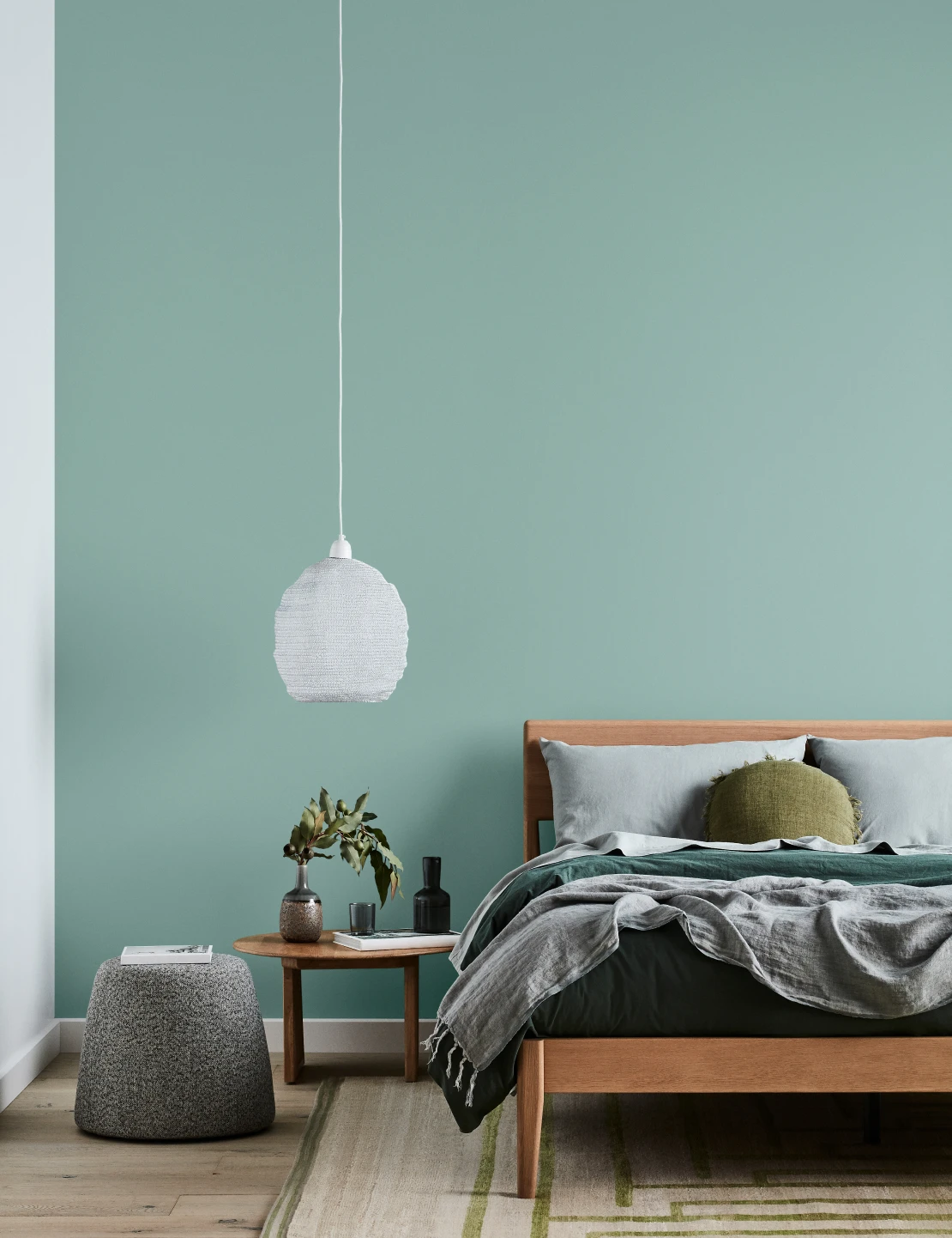 Bedroom with green Tiamo coloured wall, timber bed frame, timber side table and green room styling