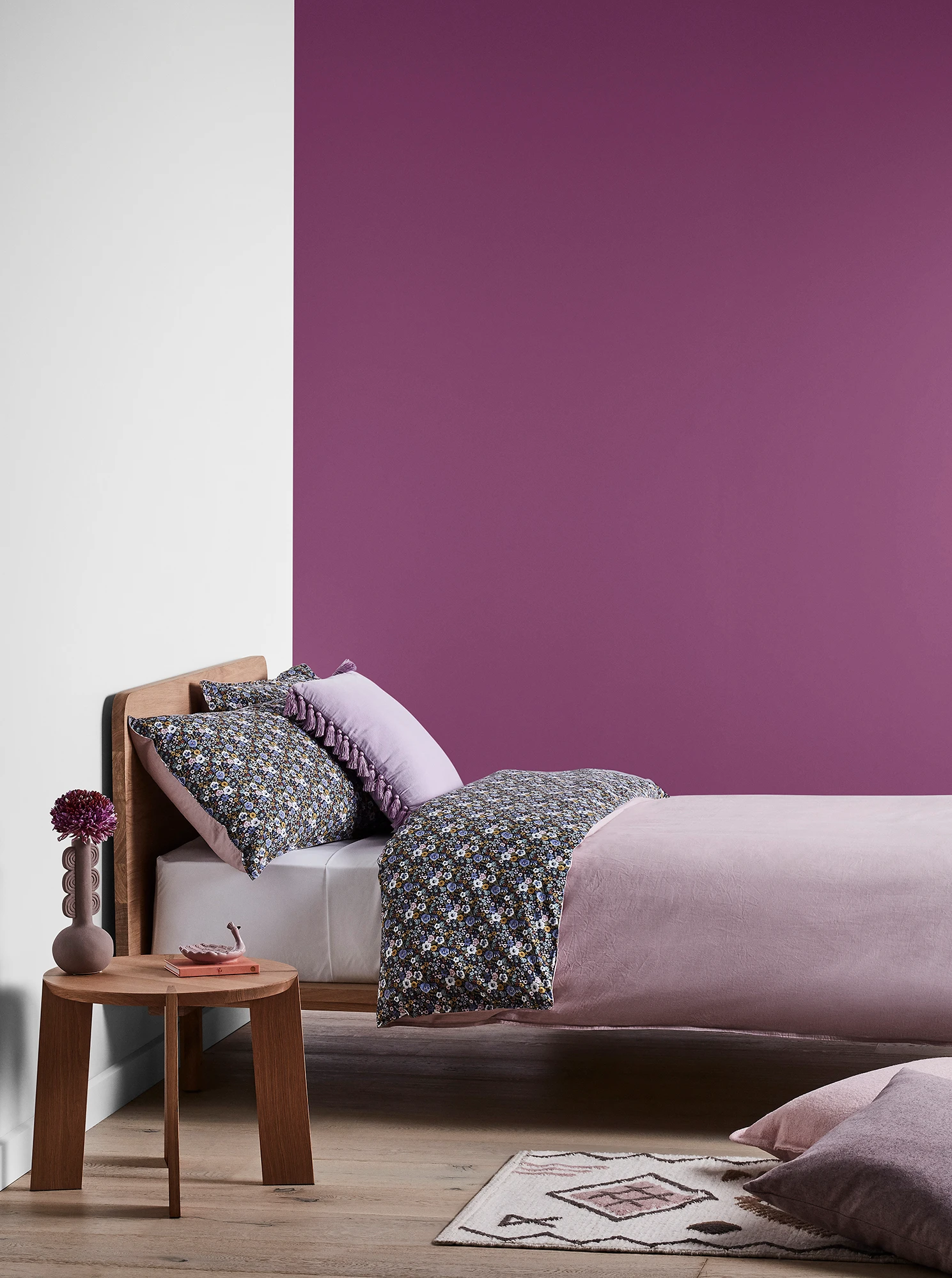 Purple bedroom with timber bed and side table and purple linens.