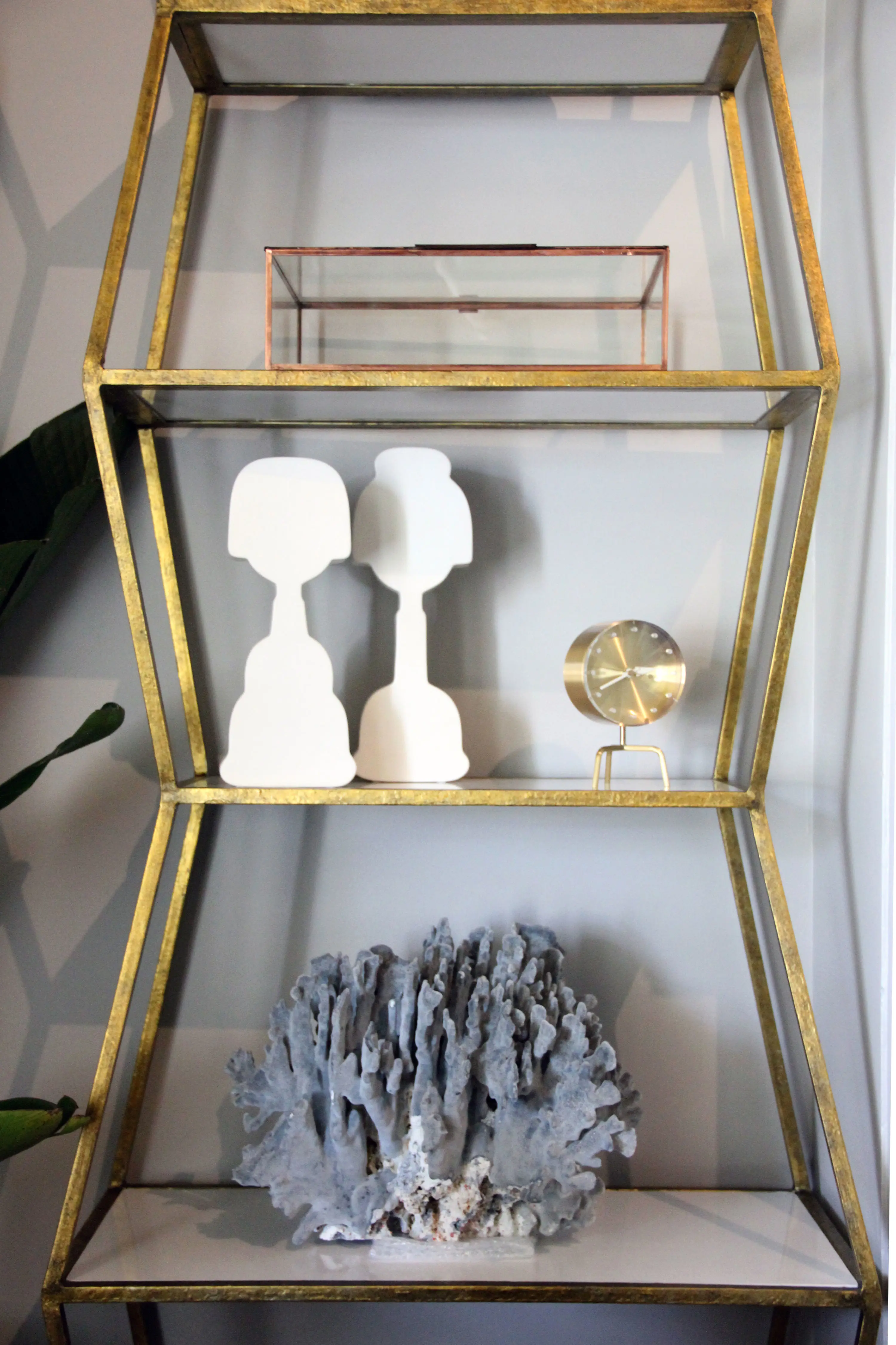 Gold shelf with gold, white and grey decor items