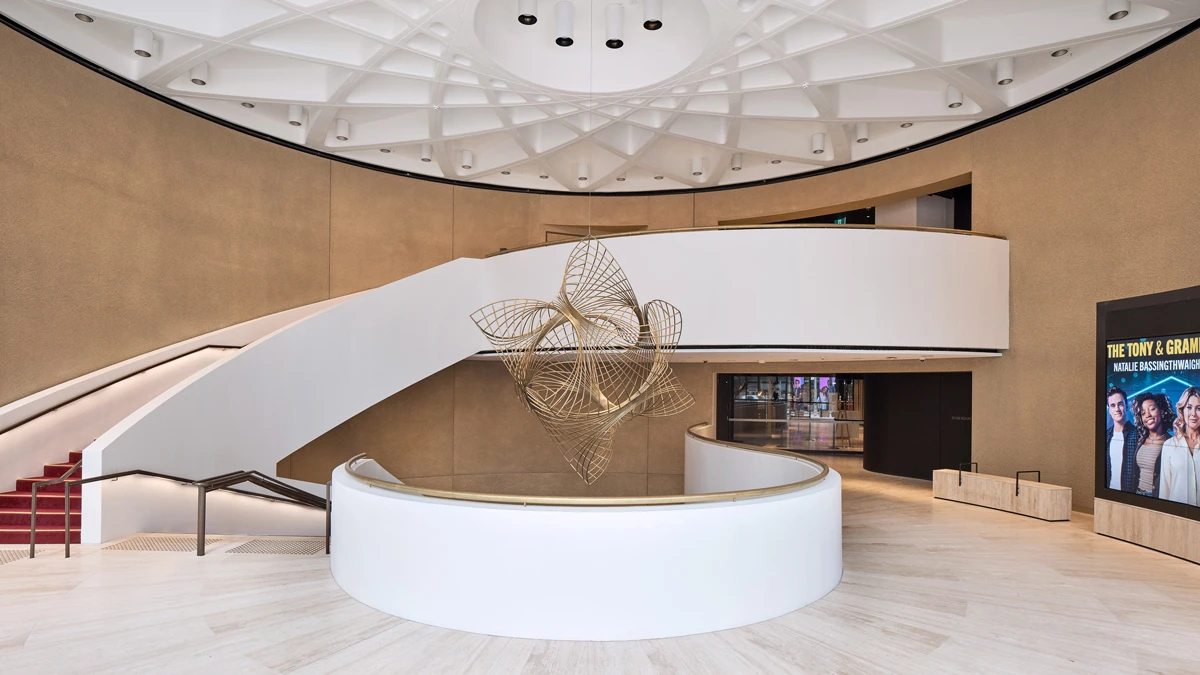 Reception area with sleek curved staircase to side and sculpture behind reception desk.