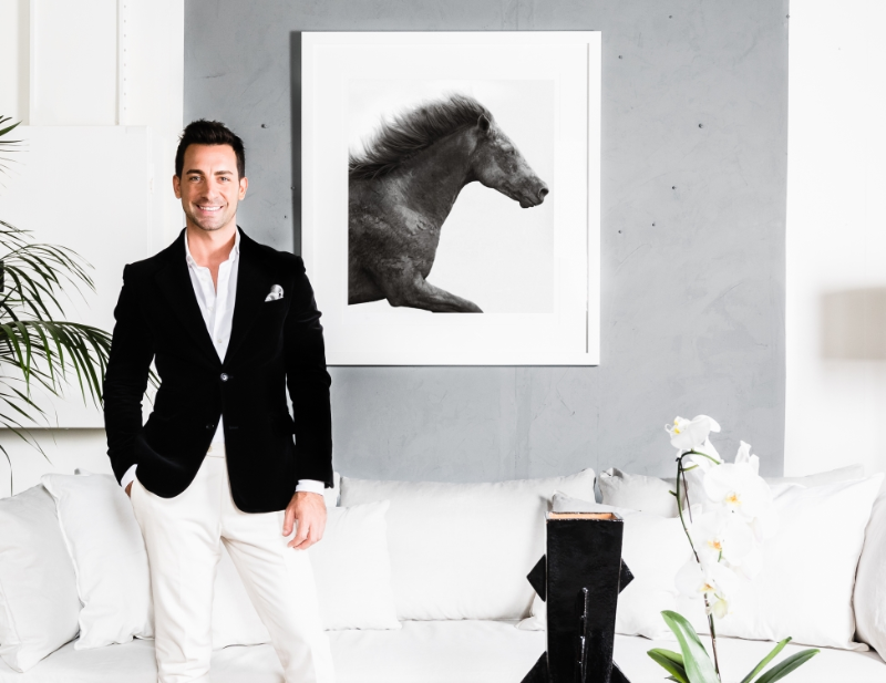 Interior designer Steve Cordony in living area in front of concrete-style wall with photograph of black horse.