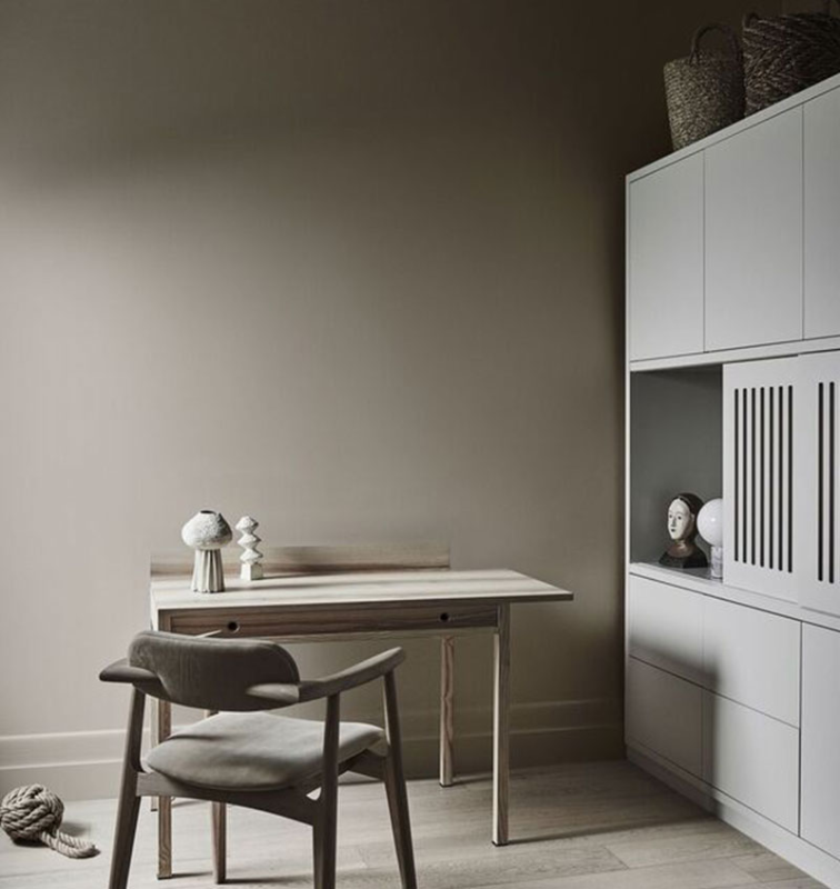 Chair at wooden desk. There's a white shelf next to the desk with a head statue on it.