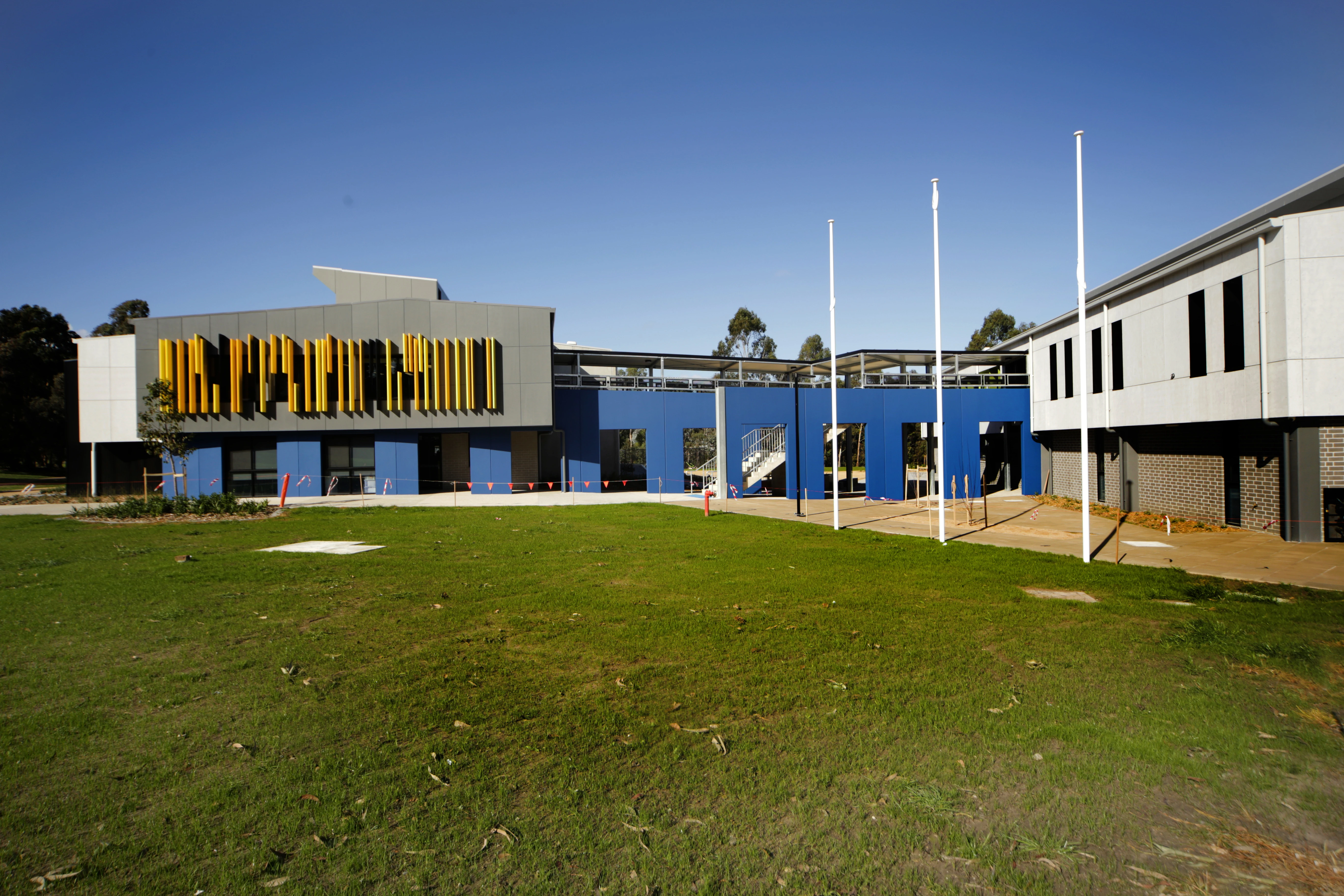 exterior school with blue feature wall and yellow louvres.