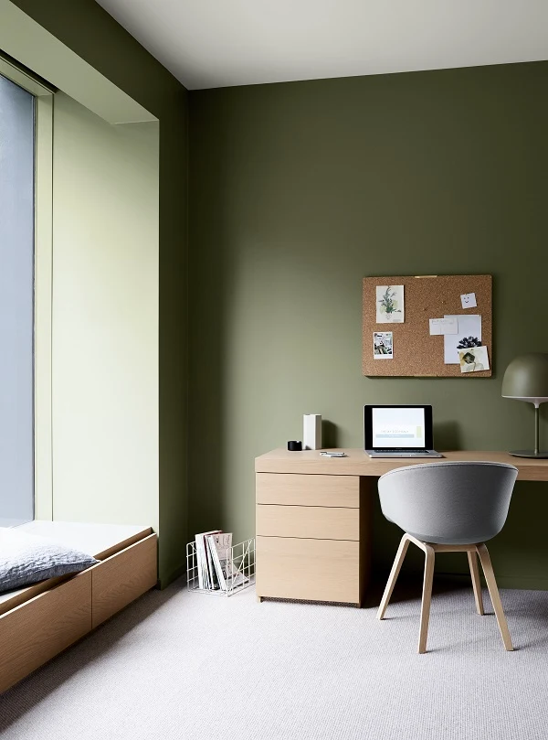 olive green wall in study, timber desk and beanchseat, timber and grey chair, neutral tones