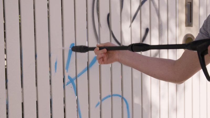 High pressure hose on picket fence with graffiti
