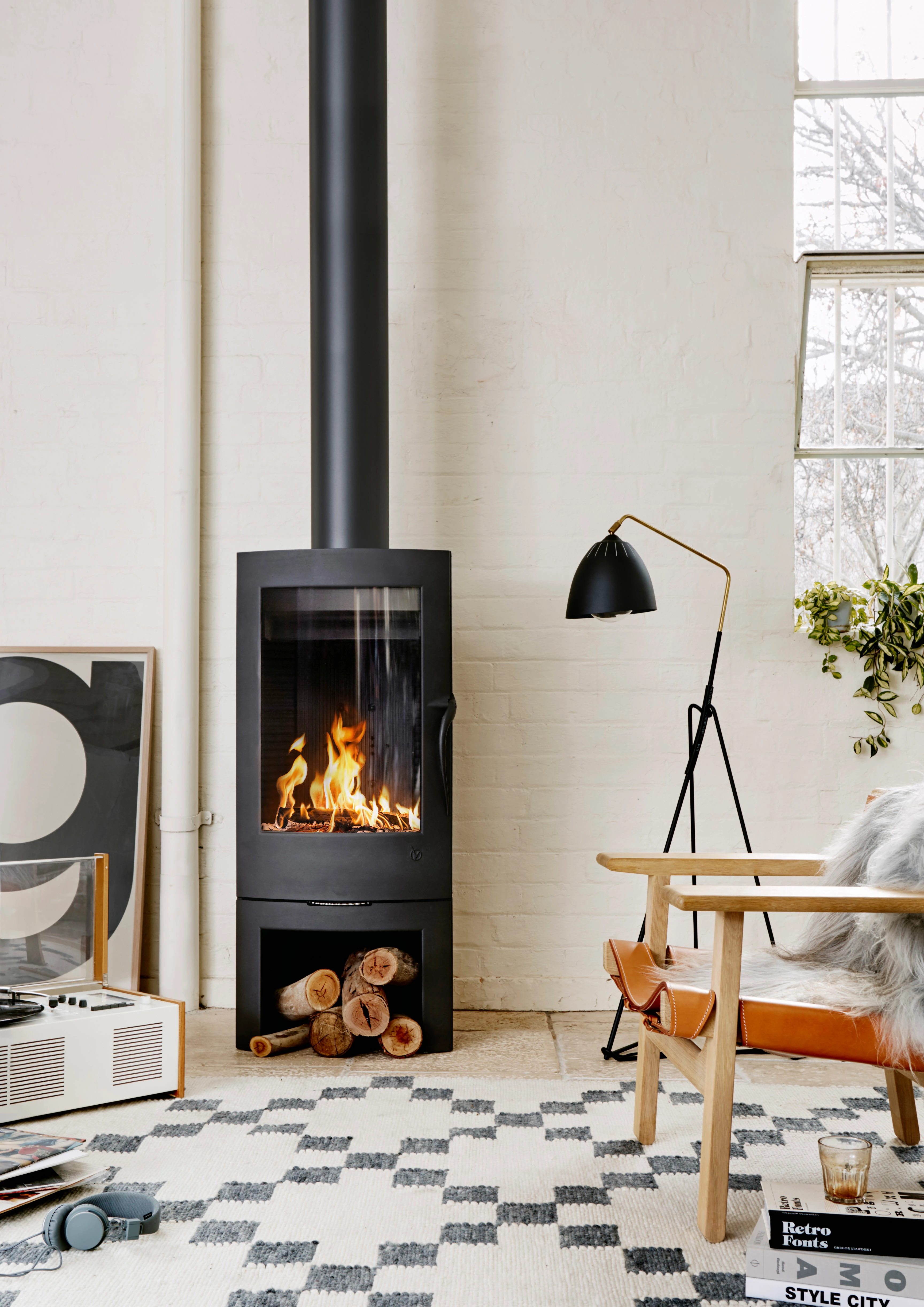 interior closeup of fireplace on white brick wall with lamp and chair. 