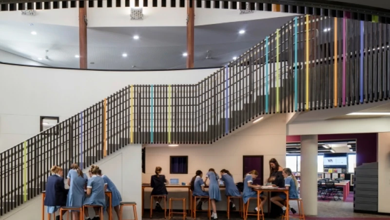 Internal school staircase with black and coloured railing and bars.