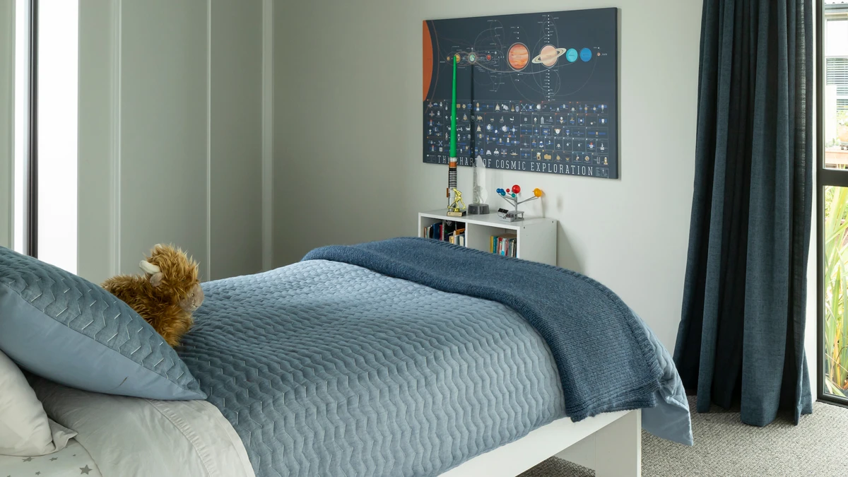 Child's bedroom with galaxy poster on wall and curtains across windows.