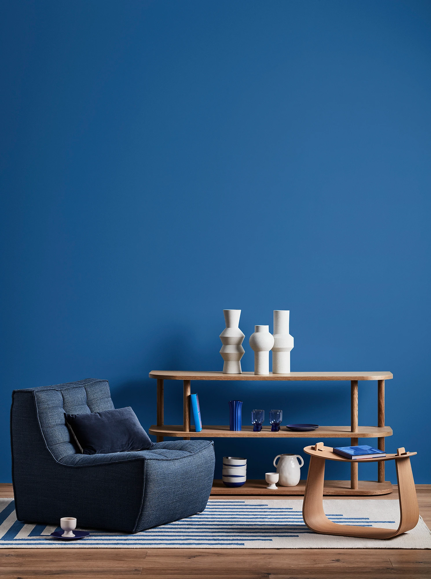 Blue living room with blue armchair and timber side tables.