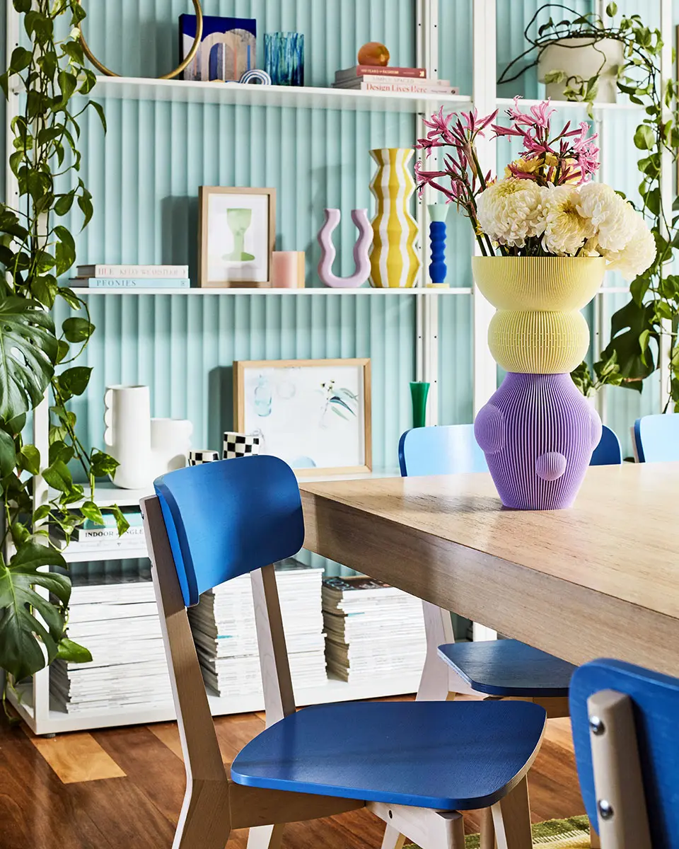 Blue chair at timber dining table with purple and yellow vase