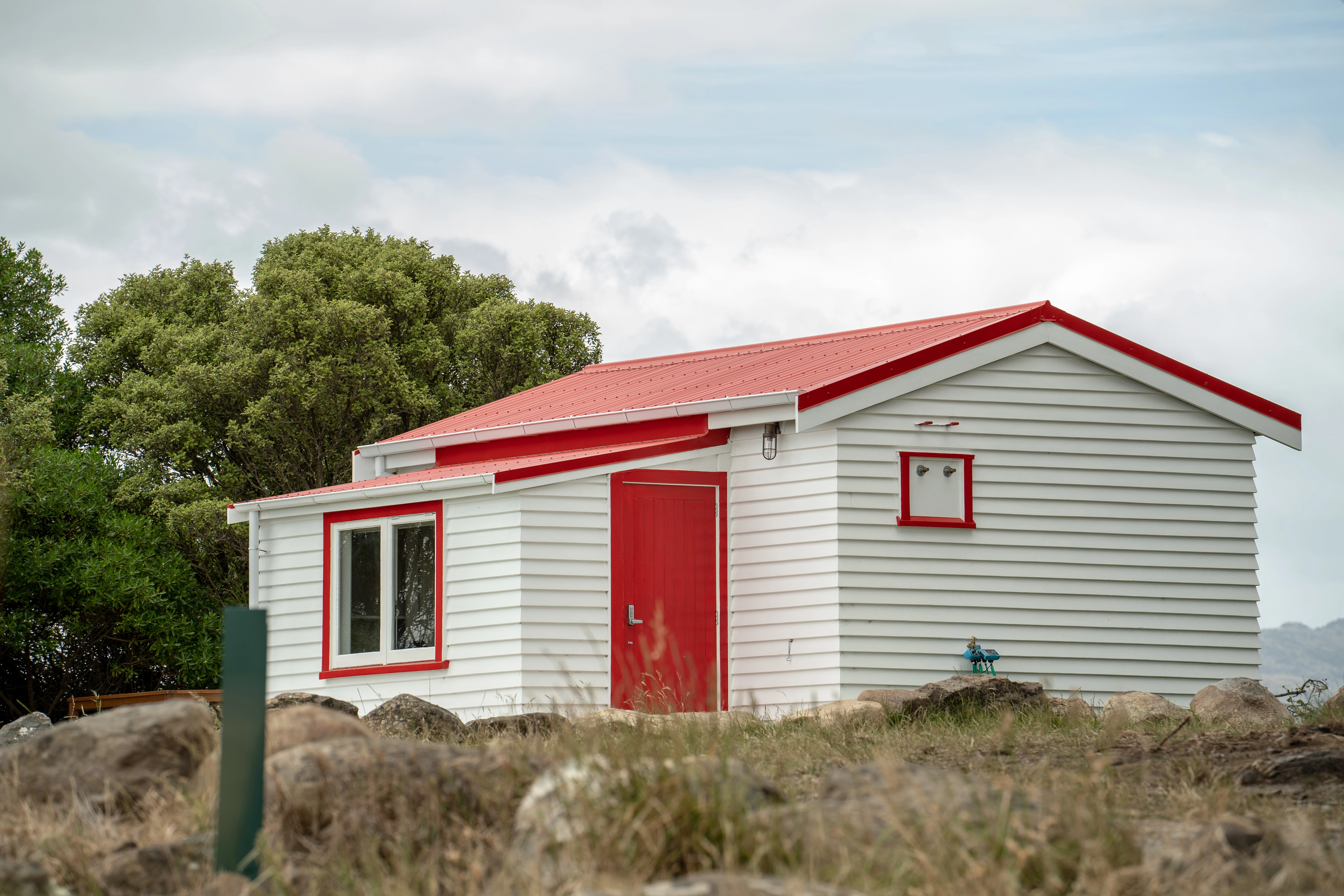 The Lighthouse Cottage is white with red trims and a red roof