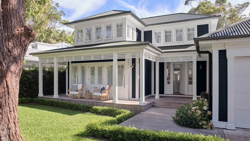 Exterior of Hamptons style home with grass and hedges surrounding footpath.