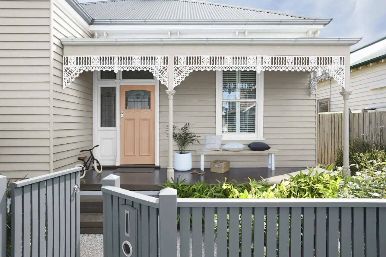 Neutral single fronted weatherboard with white trim and peach door, darker grey picket fence.