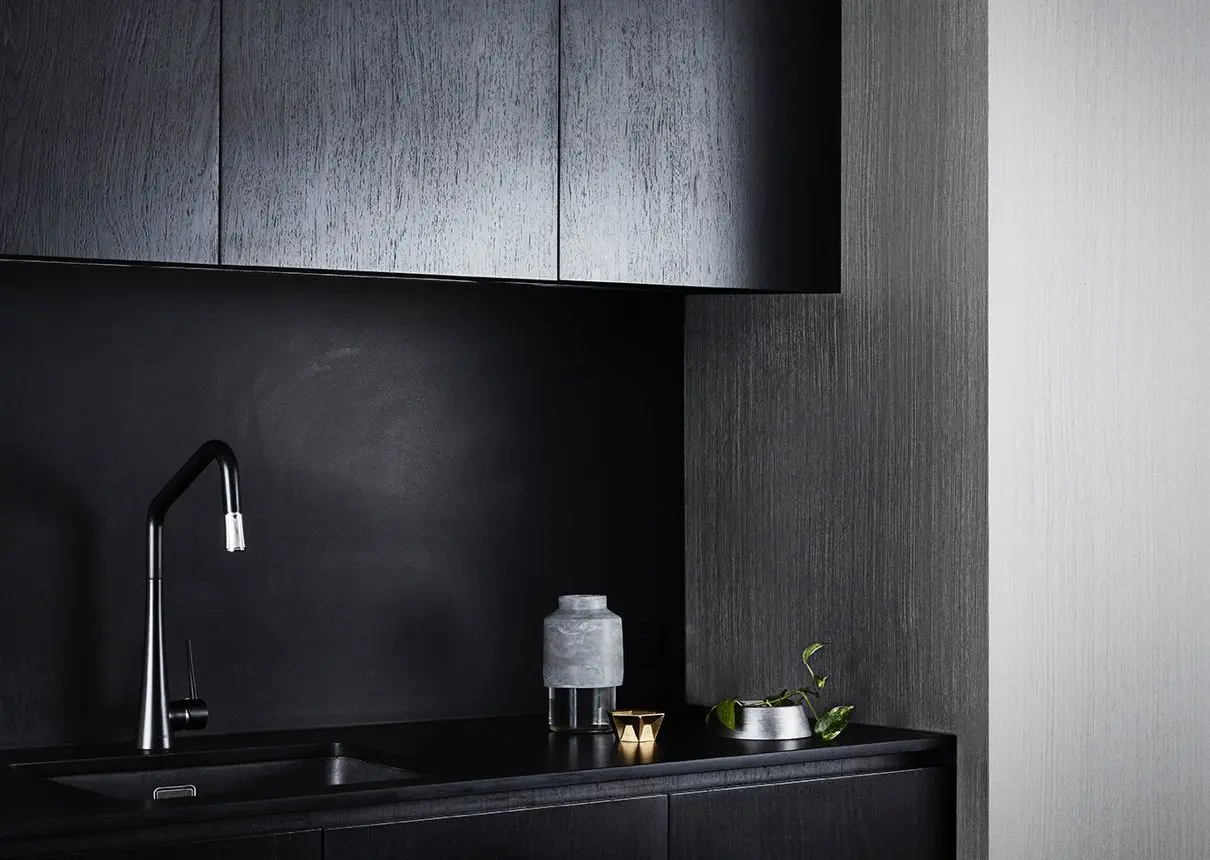 Stainless steel effect featured in small kitchenetter with black cabinetry and a sink. 