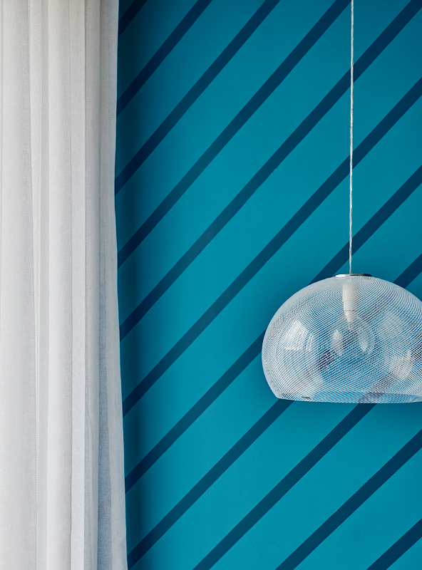 A hanging light in front of a blue striped wall in Dulux Sir Edmund and Bondi