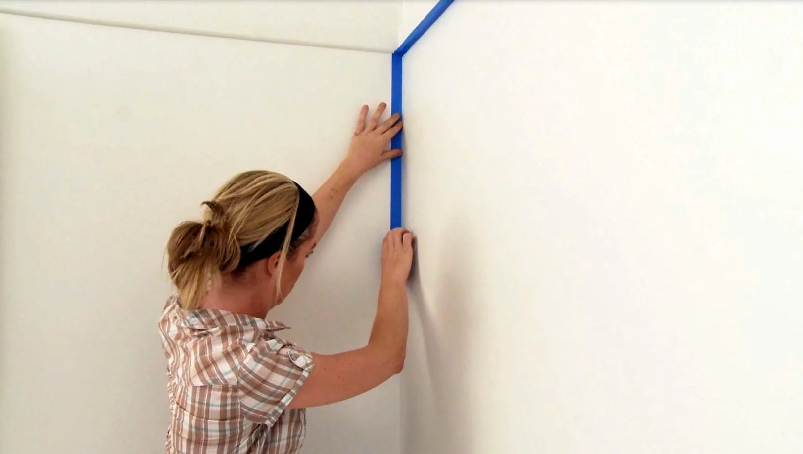 Woman using masking tape to protect area in preparation for painting