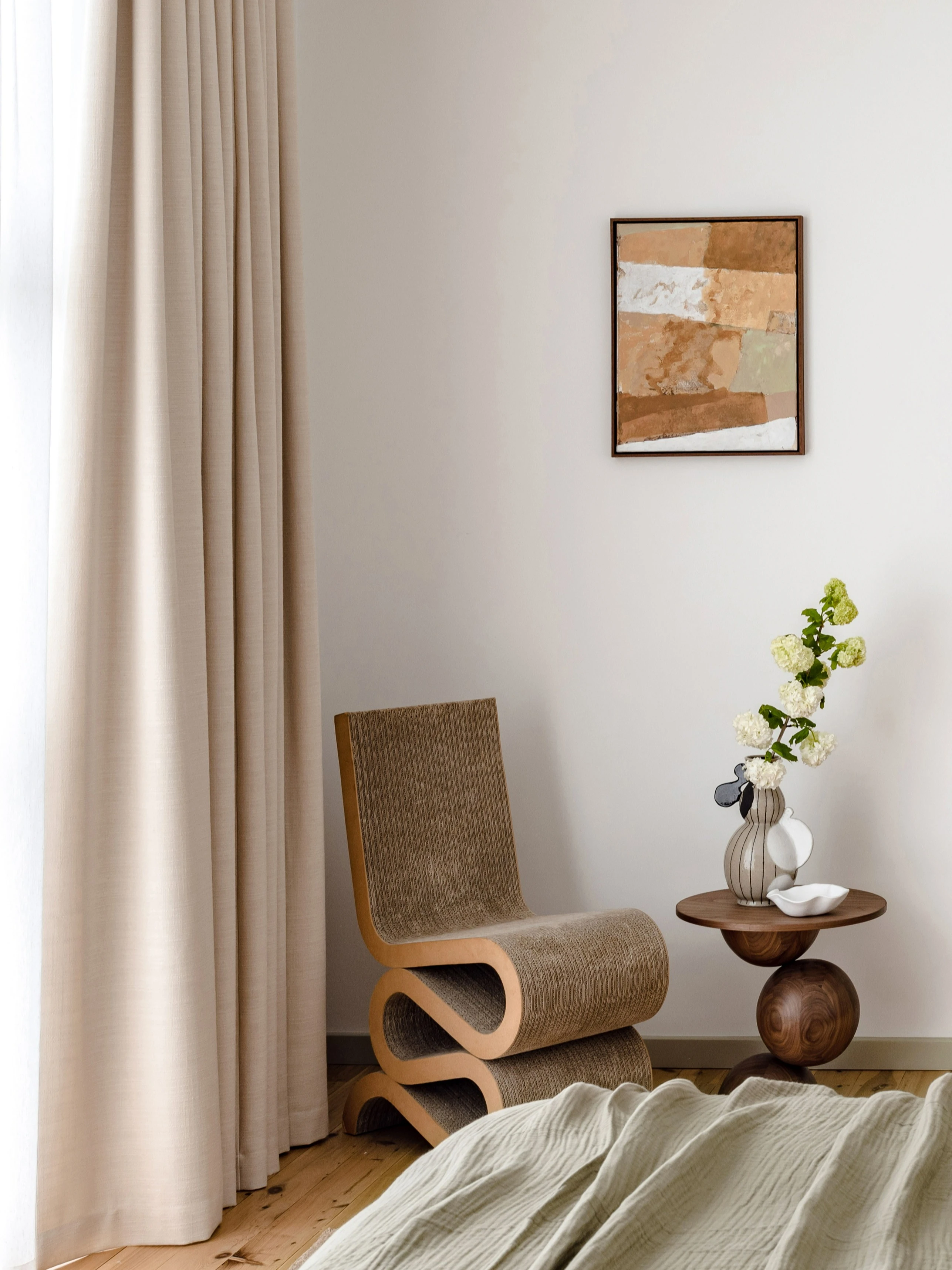 Neutral interior featuring wiggle chair and wooden sphere sculpture side table