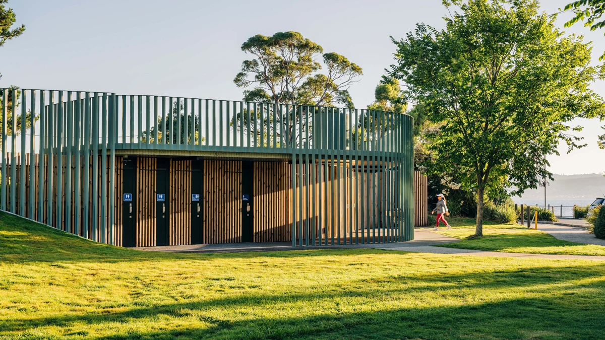 Public toilets with coloured panelling and tree to side.