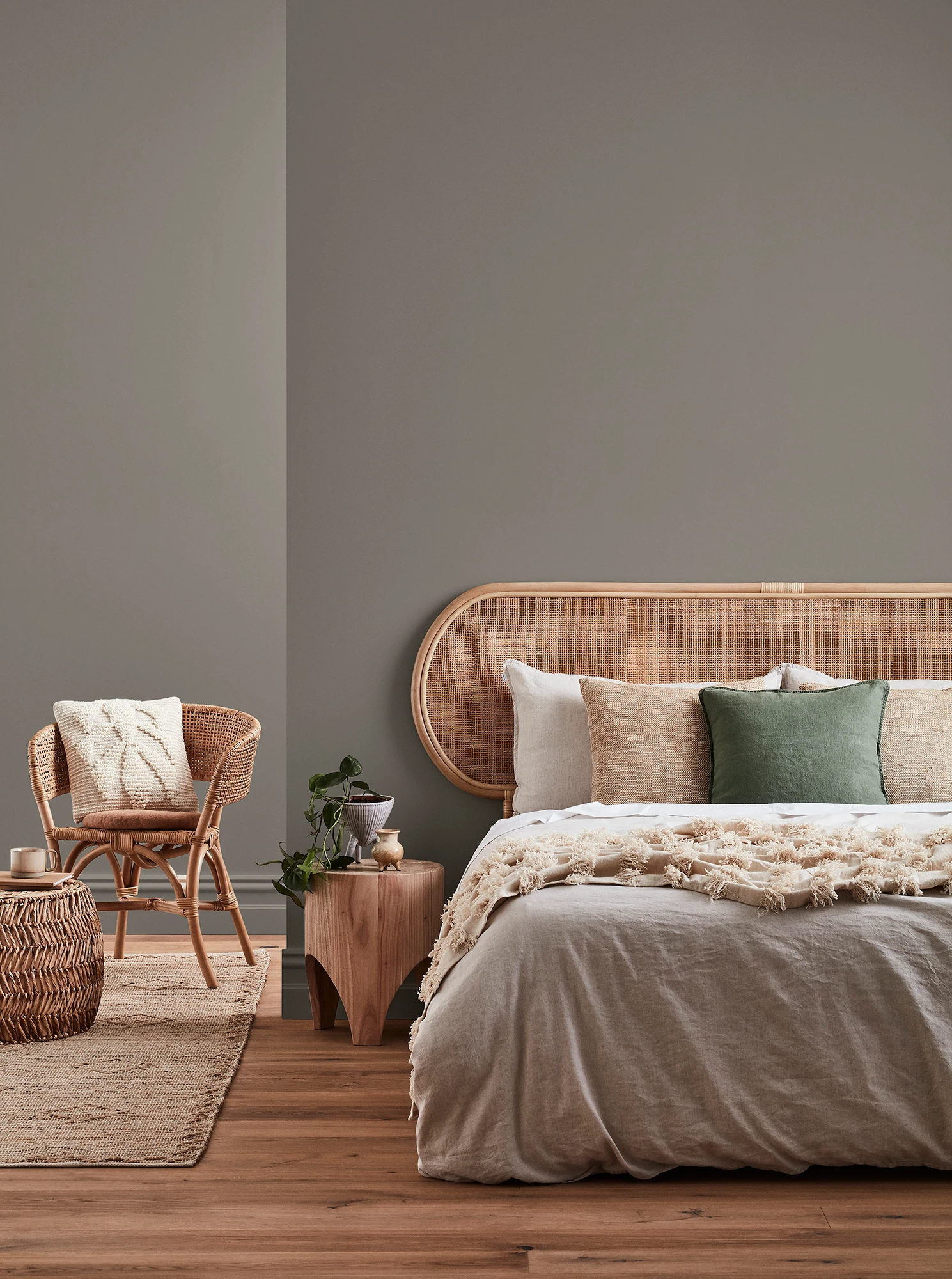  Neutral-coloured bedroom with rattan headboard and chair and neutral linens.