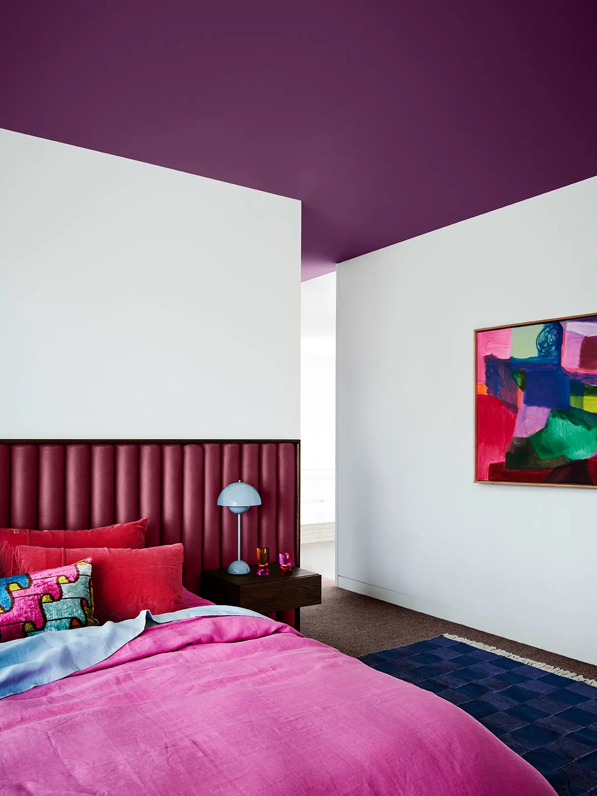 Bedroom with purple bedhead and ceiling and white walls