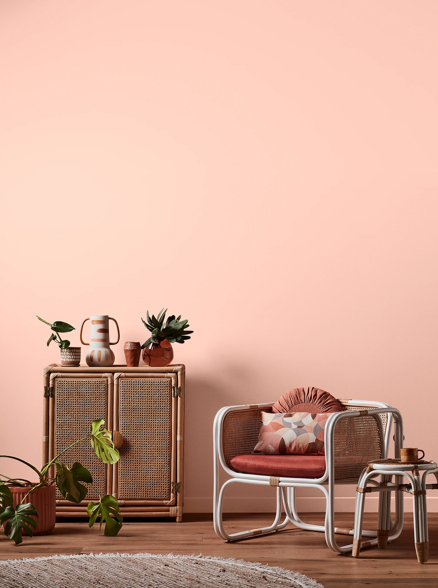 Pink living room with pink armchair, wooden side table and sideboard with white and pink decor.