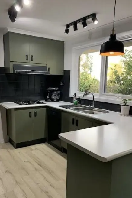 Kitchen with dark green cabinetry, white benches and ceiling