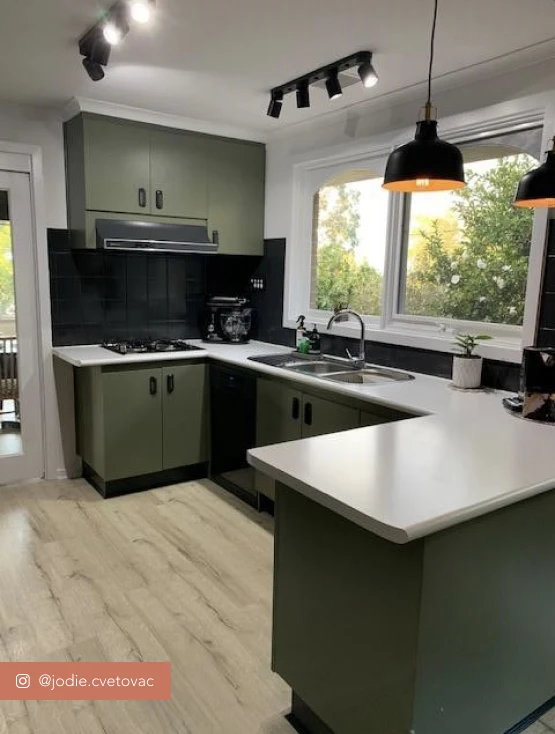 Kitchen with dark green cabinetry and white benchtops