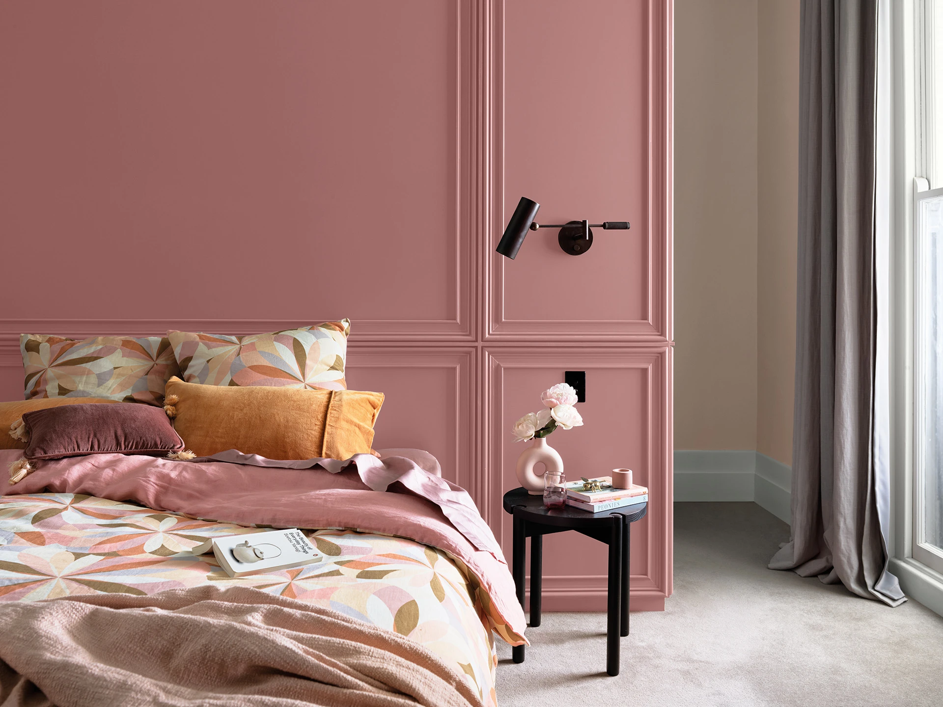 Pink shade bed with side table, books sitting on messily made bed. 
