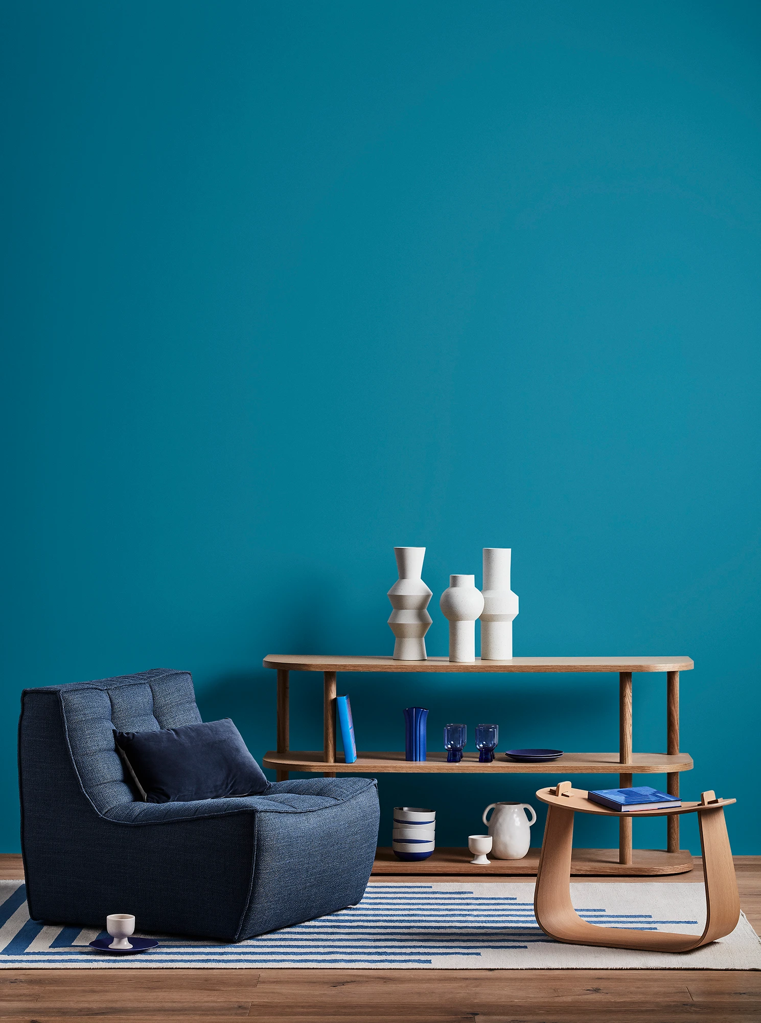 Blue living room with blue armchair, wooden coffee table and shelves with blue and white decor.