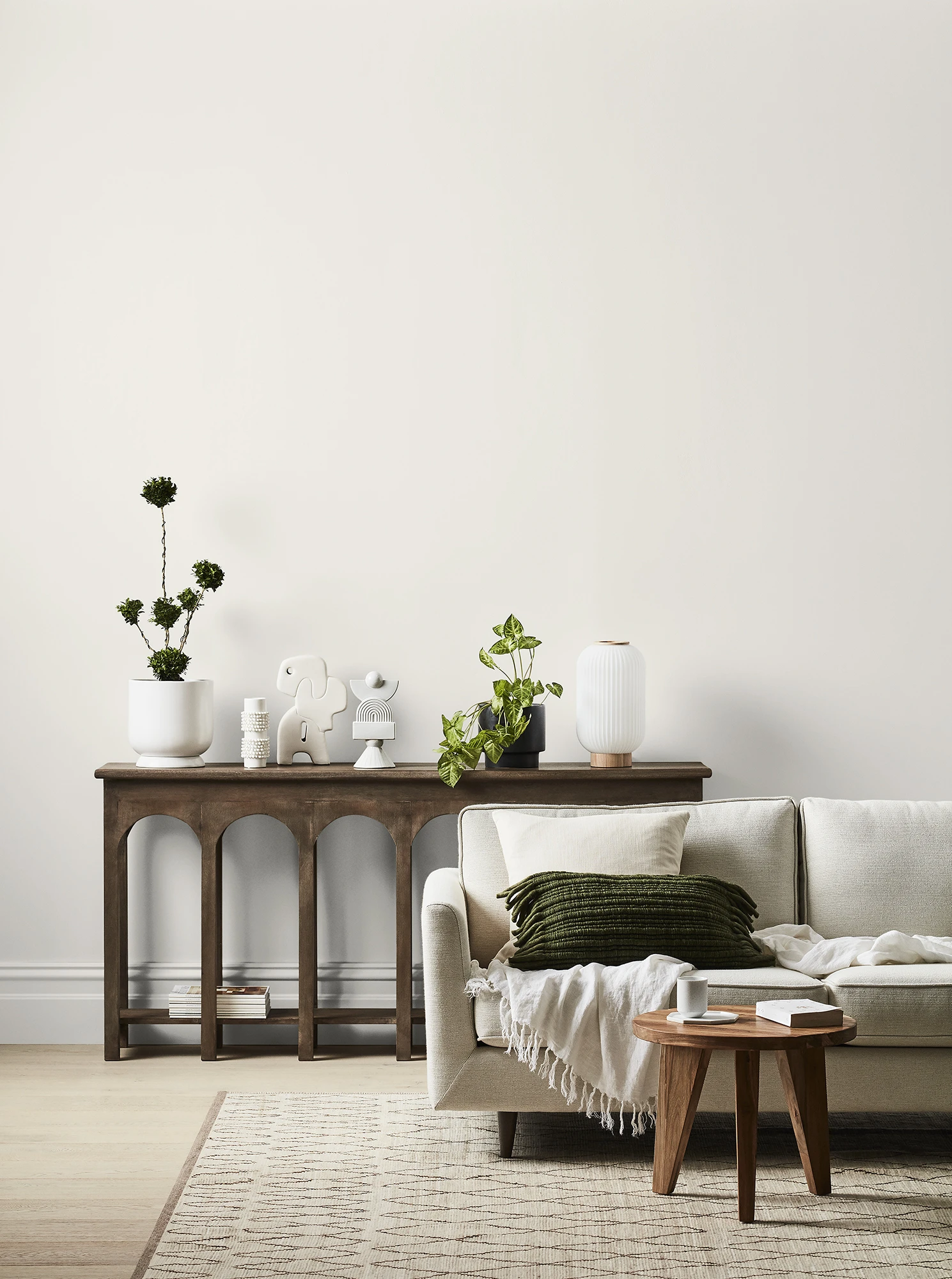 White and neutral themed living room with couch and buffet table against wall with decorative items.